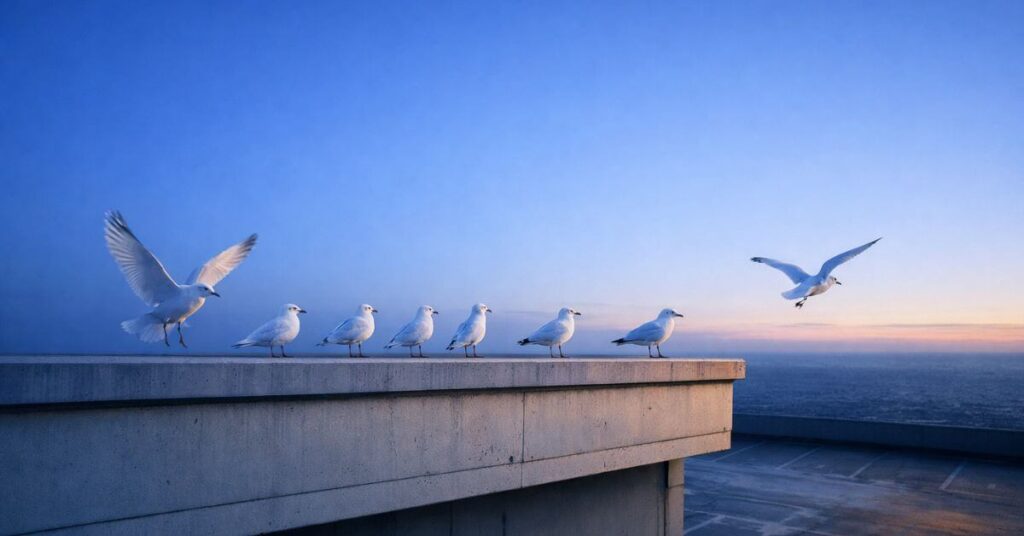 White birds lifting off a rooftop ledge into a deep blue morning sky. Featured image for the poem From Concrete to Sky on Sayspire.
