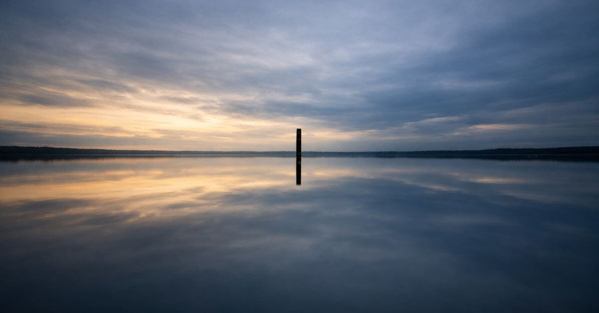 A glassy lake reflecting the open sky at dusk. Featured image for the poem At Week's End on Sayspire.