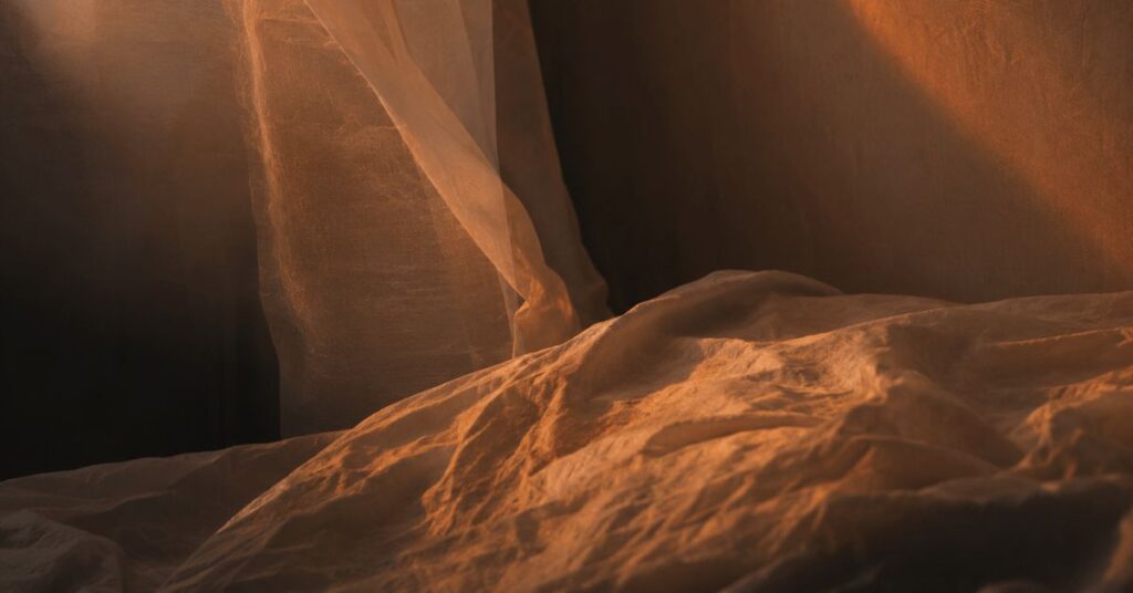 Warm amber light over rumpled linen, a thinking of you poem by Joshua Cintron on quiet, lingering calm.